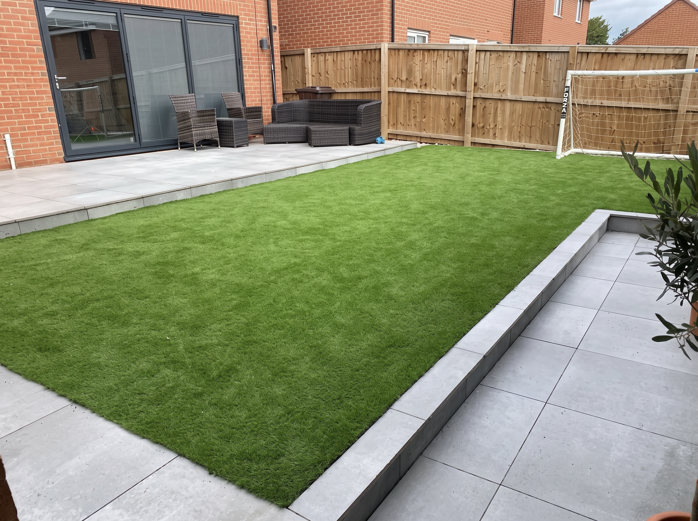 Finished back garden with artificial lawn and grey porcelain paving